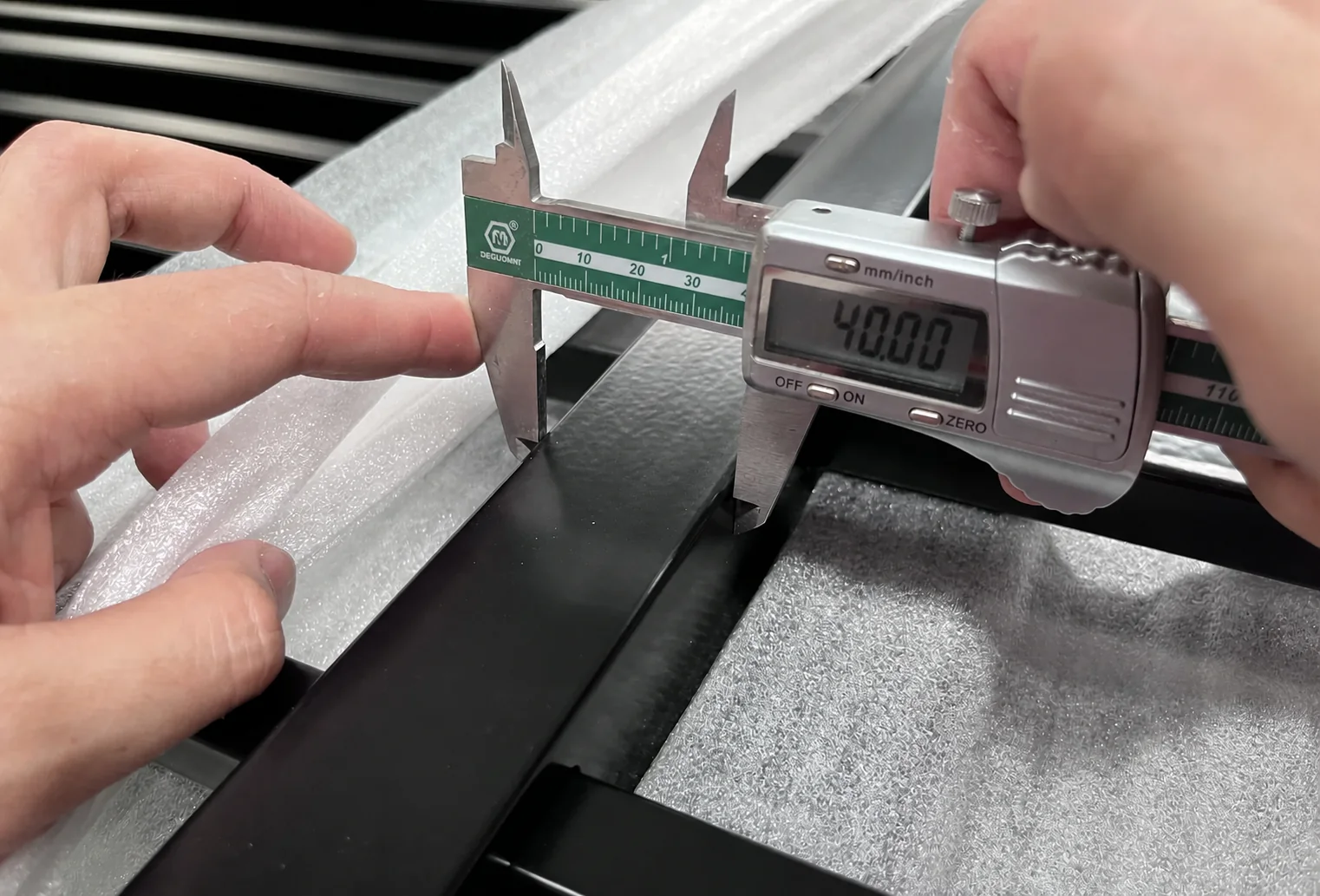 Digital caliper showing 40.00 mm during steel fence component inspection