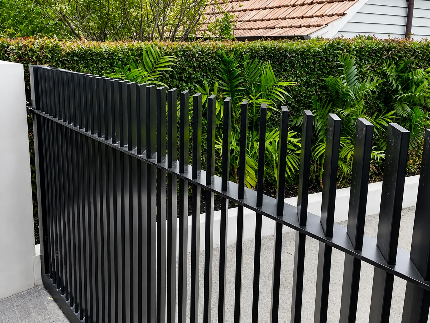 Black vertical 45 degree blade fencing installed beside a landscaped residential path