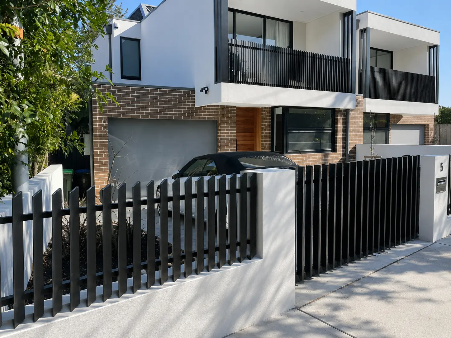 Black 45 degree blade fencing installed around a modern townhouse and front boundary walls