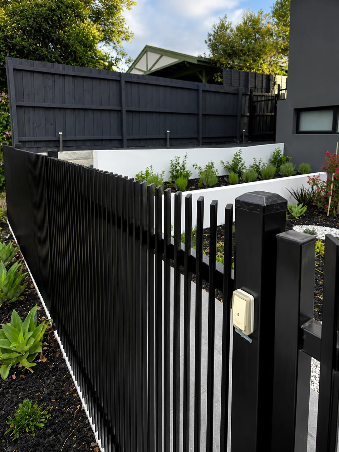 Black 45 degree blade fencing installed around a modern residential garden