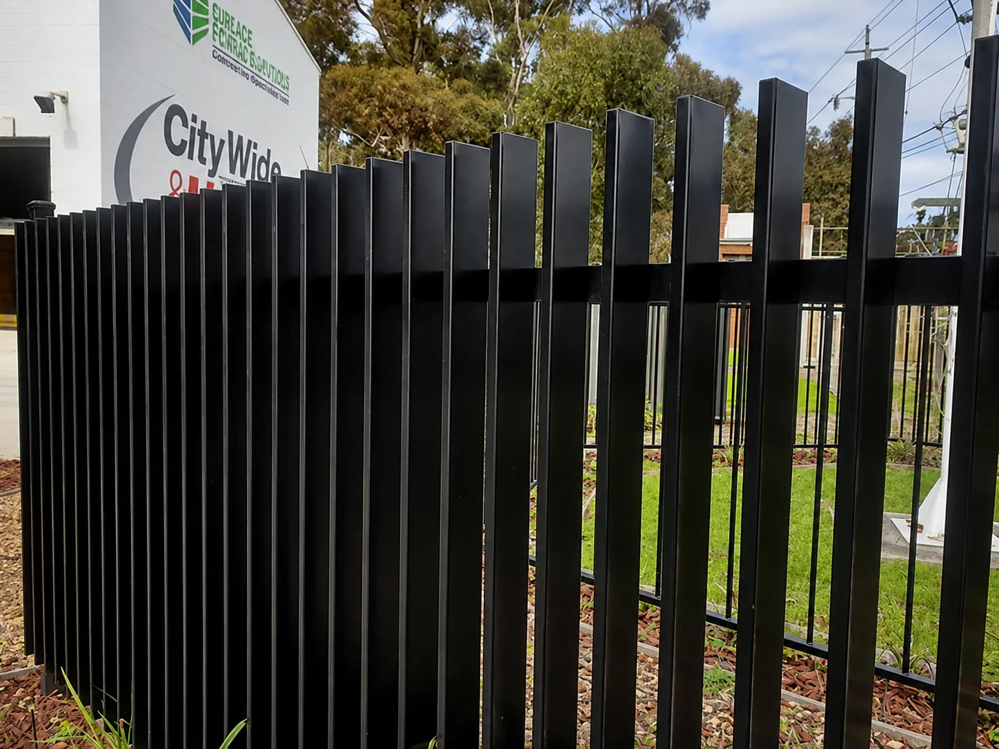 Close view of black vertical aluminium blade fencing at a commercial property boundary