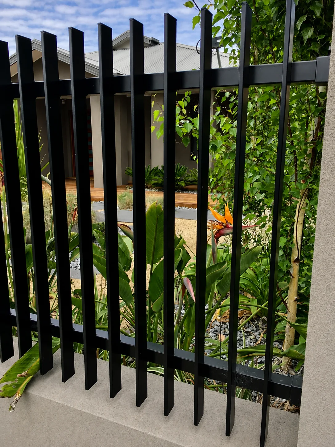 Black aluminium blade fencing screening a landscaped residential garden