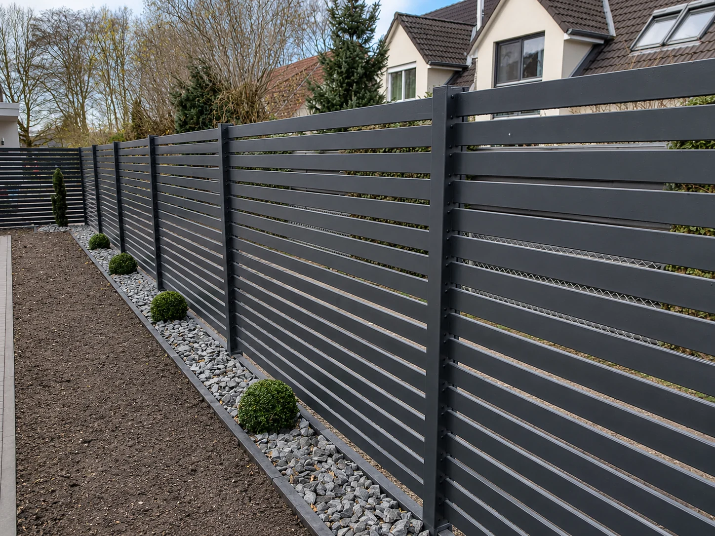 Dark slatted privacy fence installed along a residential garden