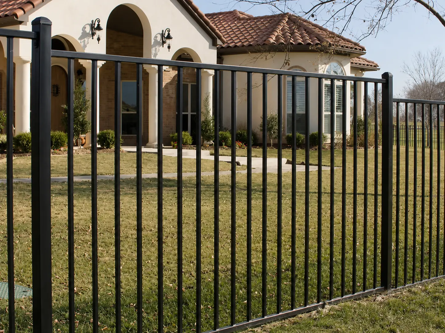 Black flat top steel fence panel installed in front of a residential property