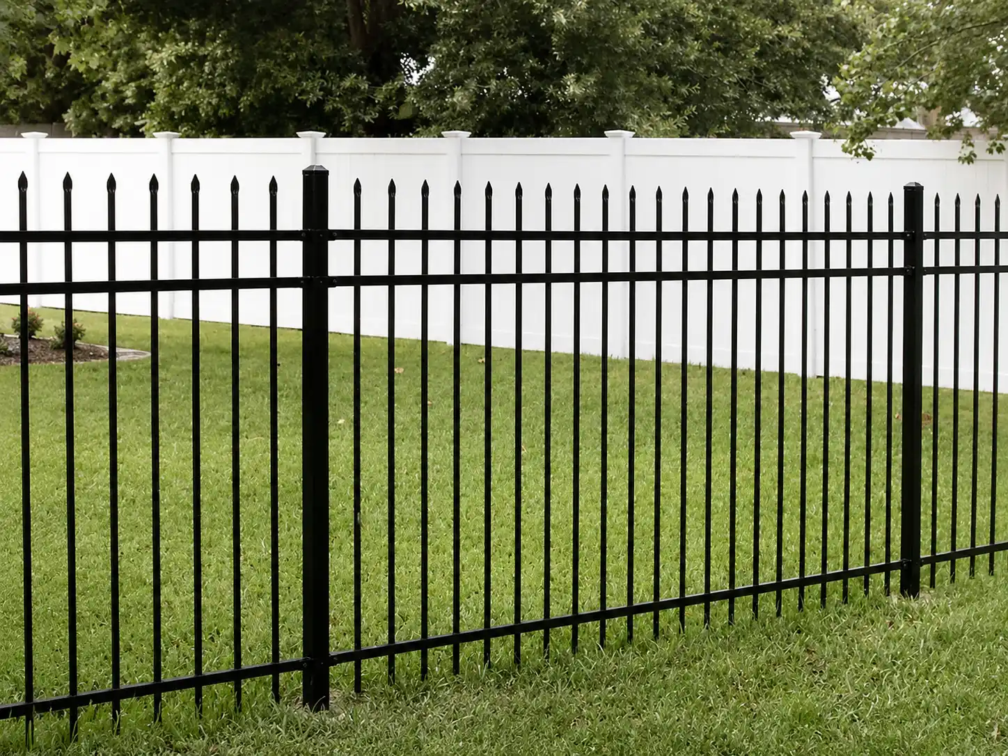 Black steel spear top fence panels with three horizontal rails installed on a lawn